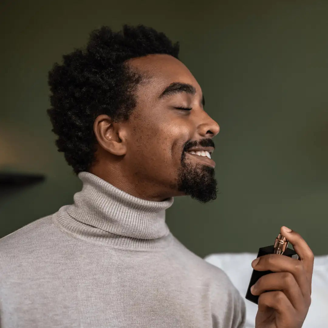 Confident man in turtleneck sweater applying luxury men’s perfume – masculine fragrance lifestyle image for cologne advertising.